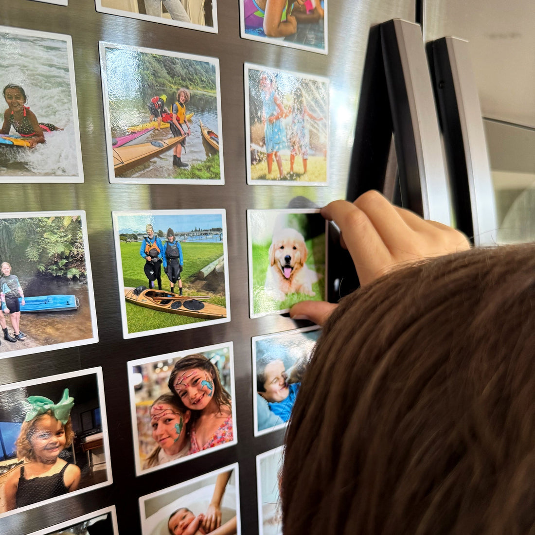 Custom photo magnets displayed on a fridge with a child's hand reaching for them — a personalised gift from Magnapix